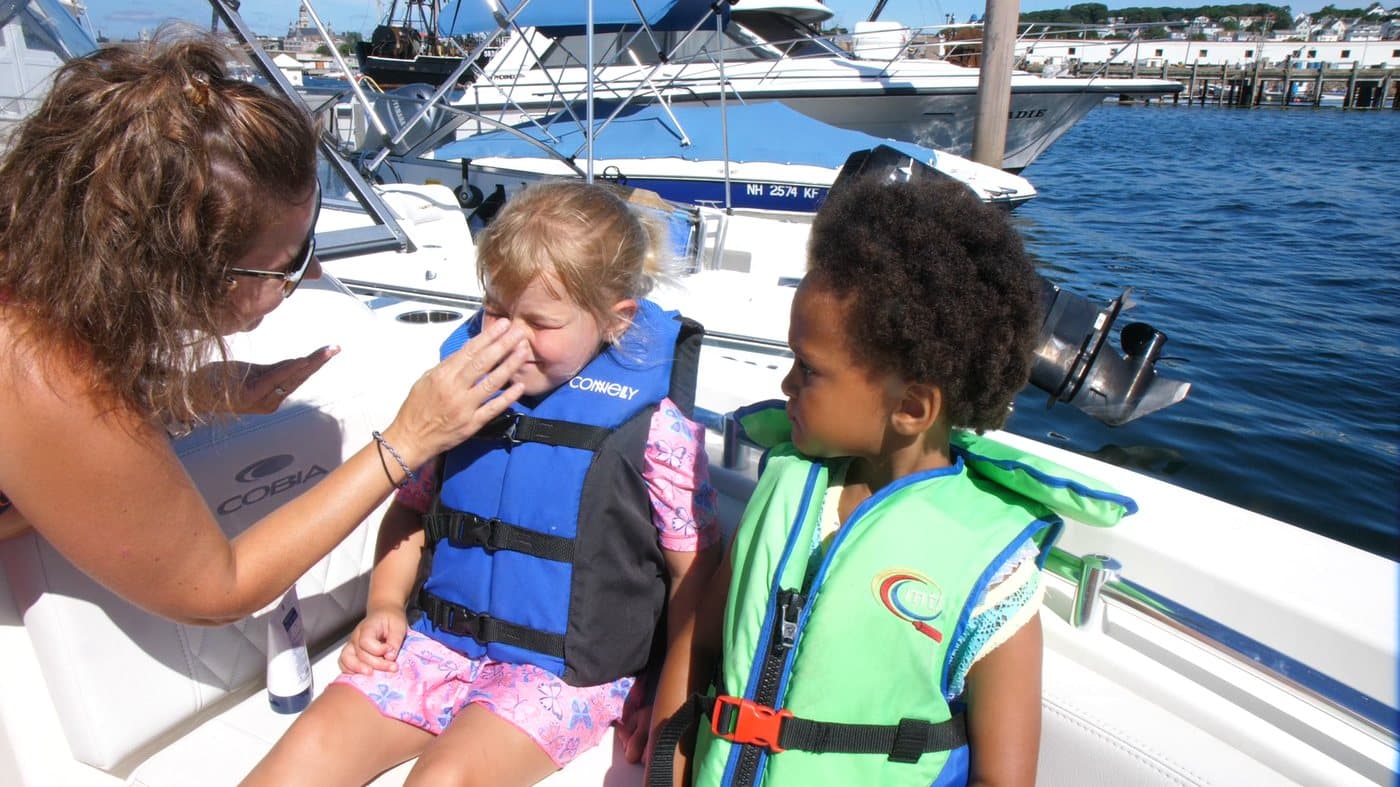 A mom and her kids in life jackets enjoying a day on the boat